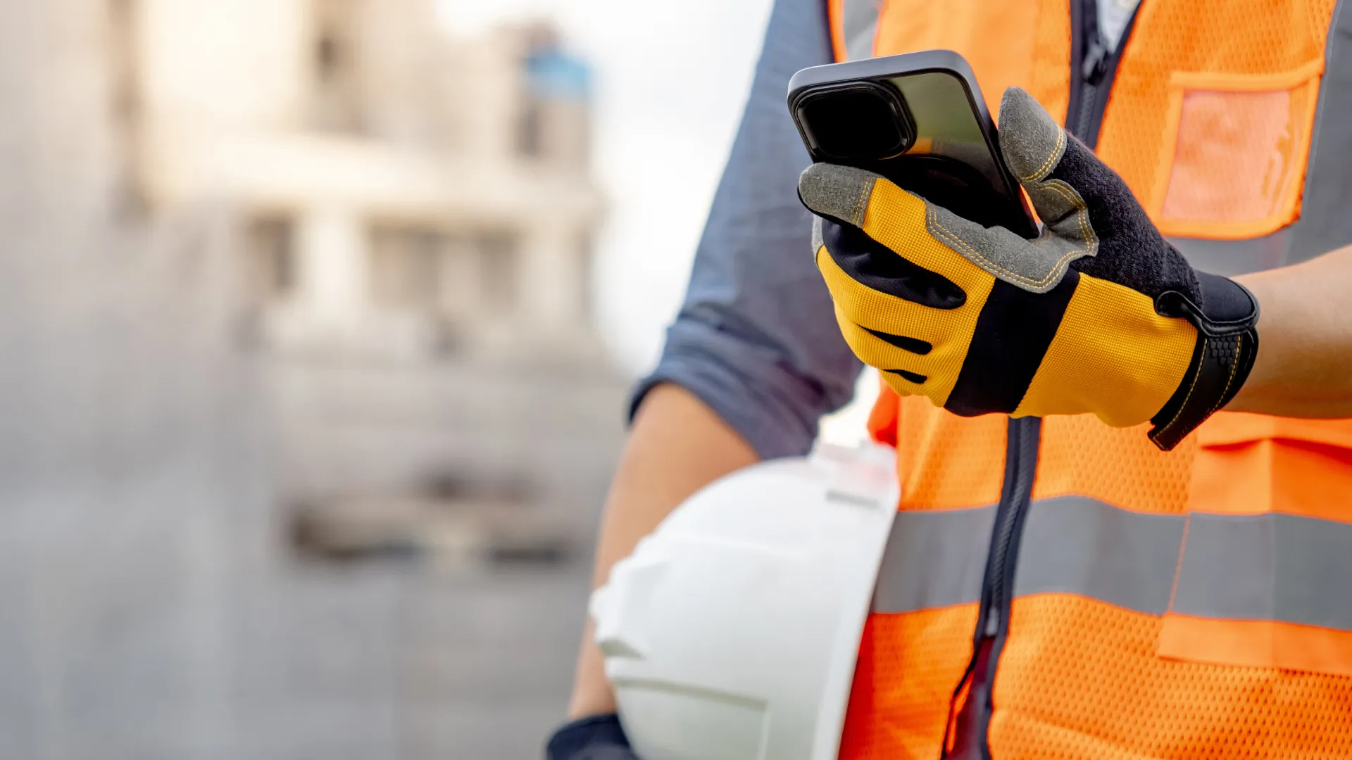 A field engineer in a high-visibility jacket taking a call on a mobile outdoors.